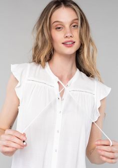 A women's classic bohemian white button-front blouse, perfect for spring. Click to shop LA's #1 destination for affordable boho tops! Elegant Summer Tops With Drawstring Tie, Summer Blouse With Lace Trim And Flutter Sleeves, Summer Lace Trim Flutter Sleeve Blouse, Summer Flutter Sleeve Blouse With Lace Trim, White Tie Neck Blouse For Summer, Summer Tops With Short Sleeves And Drawstring Tie, Spring White Blouse With Tie Sleeves, White Blouse With Tie Sleeves For Spring, Summer Tops With Drawstring Tie And Short Sleeves