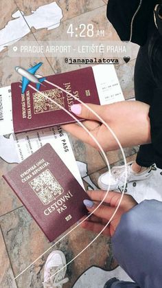 a woman is holding two passport cards in her hand and an airplane on the ground