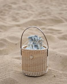 a wicker basket with cloths in the sand