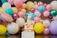 a birthday cake sitting on top of a table surrounded by balloons