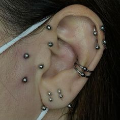 a woman with piercings on her ear and behind the ear is a pair of silver balls