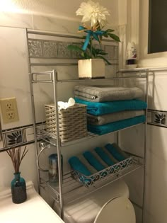 a bathroom shelf with towels and other items on it in front of a toilet bowl