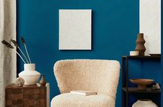 a living room with blue walls and white furniture, including a chair in the foreground