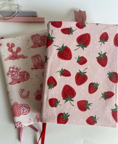 two wrappings with strawberries on them are sitting next to each other in front of a pair of reading glasses