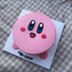 a pink cake with eyes and nose on top of a piece of paper that says fud suho