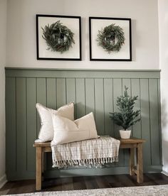 two christmas wreaths are hanging on the wall above a bench with pillows and blankets