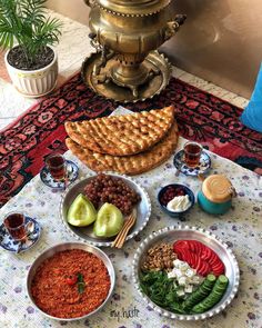 a table topped with bowls filled with food next to two plates of fruit and vegetables