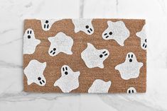 a brown door mat with ghost faces on it and white trim around the edges, in front of a marble background