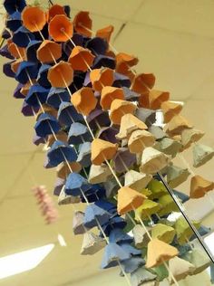 an arrangement of colorful paper hearts hanging from a string on a pole in a room