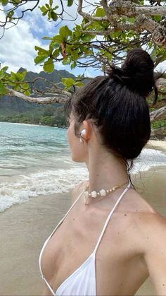 a woman is standing on the beach looking at the water