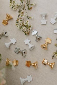 several white and gold door knobs on a table with flowers in the back ground