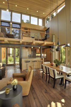 a living room filled with furniture next to a kitchen and dining room table in front of a large window