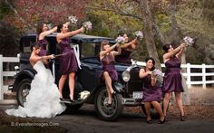 a group of women in purple dresses standing next to an old car with flowers on it