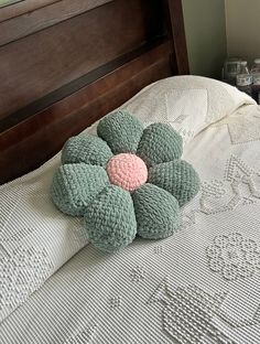 a crocheted flower pillow sitting on top of a bed with white linens