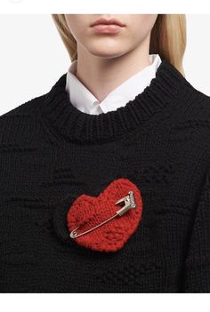 a close up of a person wearing a sweater with a heart pin on the back