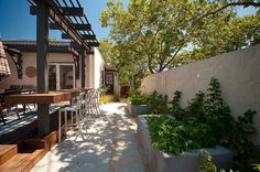 an outdoor patio with tables and chairs next to a fenced in area that has plants growing on it