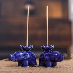 two small blue elephants sitting on top of a wooden table next to candlesticks