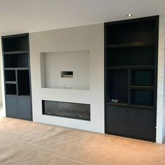 an empty living room with white walls and black bookcases on either side of the fireplace