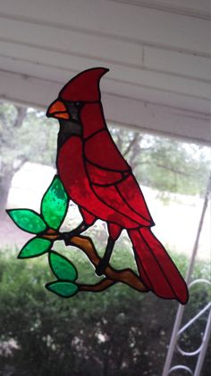 a stained glass cardinal sitting on a branch