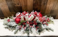 a christmas centerpiece with candy canes, ornaments and pine cones on a white table cloth