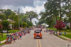 a large group of people are walking down the street in front of a parade float