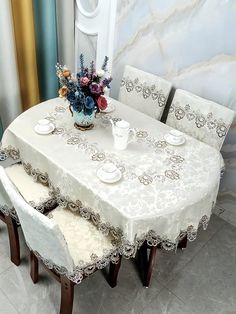 a dining room table with white chairs and a vase filled with flowers