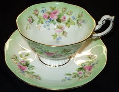 an antique tea cup and saucer with pink roses on green, gold trimmings