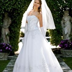 a woman in a white wedding gown and veil posing for the camera with her hand on her hip