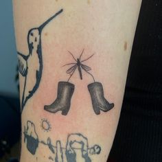 a tattoo on the arm of a woman with boots and a bird flying over it