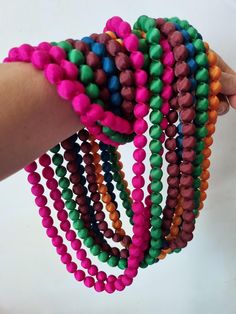 a hand holding several bracelets with different colored beads on each one wrist and the other beaded