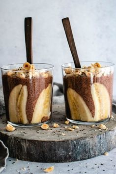 two glasses filled with dessert sitting on top of a table