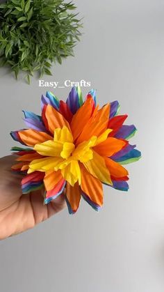 a hand is holding a colorful paper flower