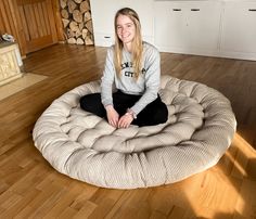 a woman sitting on top of a round bed in the middle of a living room