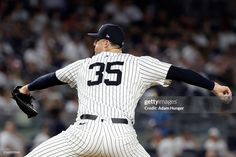 a baseball player pitching a ball on top of a field in front of a crowd