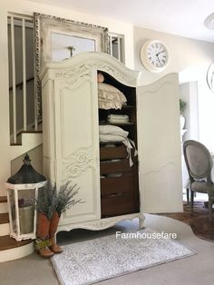 a white armoire sitting on top of a carpeted floor next to a clock