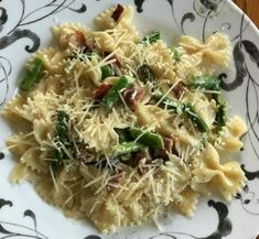 a white plate topped with pasta covered in cheese and vegtables on top of a wooden table