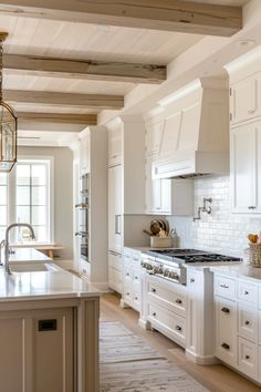 a large kitchen with white cabinets and an island in the middle is shown, along with a chandelier hanging from the ceiling