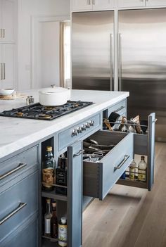 an open drawer in the middle of a kitchen counter next to a stove and refrigerator