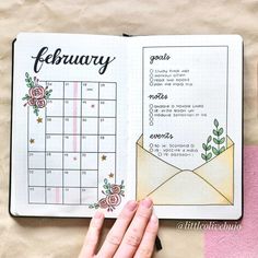 a hand holding an open planner next to a cup of coffee and a pink napkin