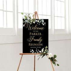 a welcome sign on an easel with greenery