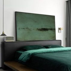 a bed with green sheets and pillows in a room next to a painting on the wall