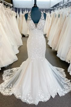 a white wedding dress is on display in a bridal room with other gowns