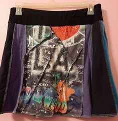 a skirt hanging up on a wall with the word la written in different colors and designs