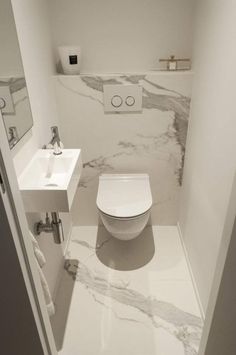 a white toilet sitting next to a sink in a bathroom under a mirror on the wall