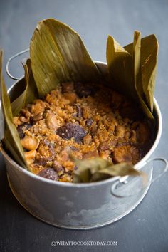 a pot filled with food sitting on top of a metal table next to a leaf