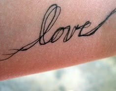 the word love written in cursive ink on someone's arm