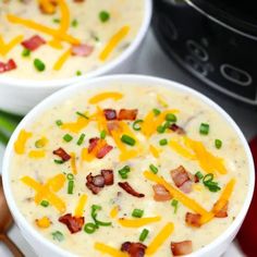 two white bowls filled with potato soup and bacon on top of green onions next to an instant pressure cooker