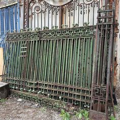 an old iron gate is sitting in front of a building that has been boarded down