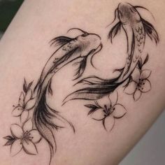 a woman's thigh with a fish and flowers tattoo on it