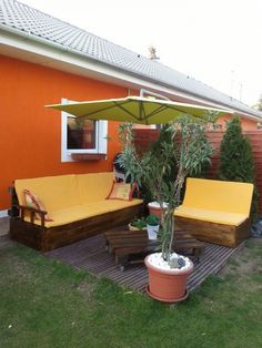 a patio with two couches and an umbrella in the middle, next to a potted plant